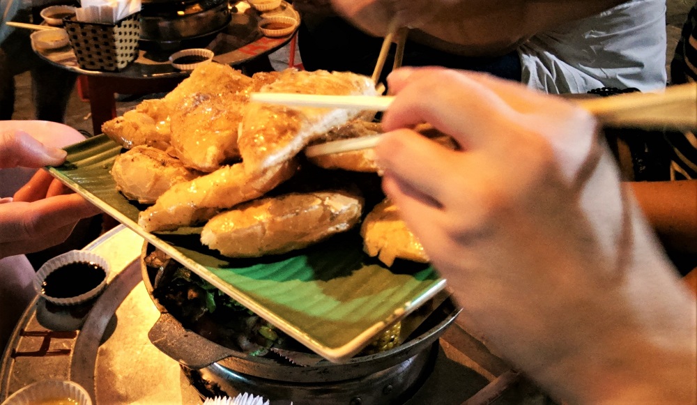 Tucking in to honey-covered bread on our street food tour in Hanoi