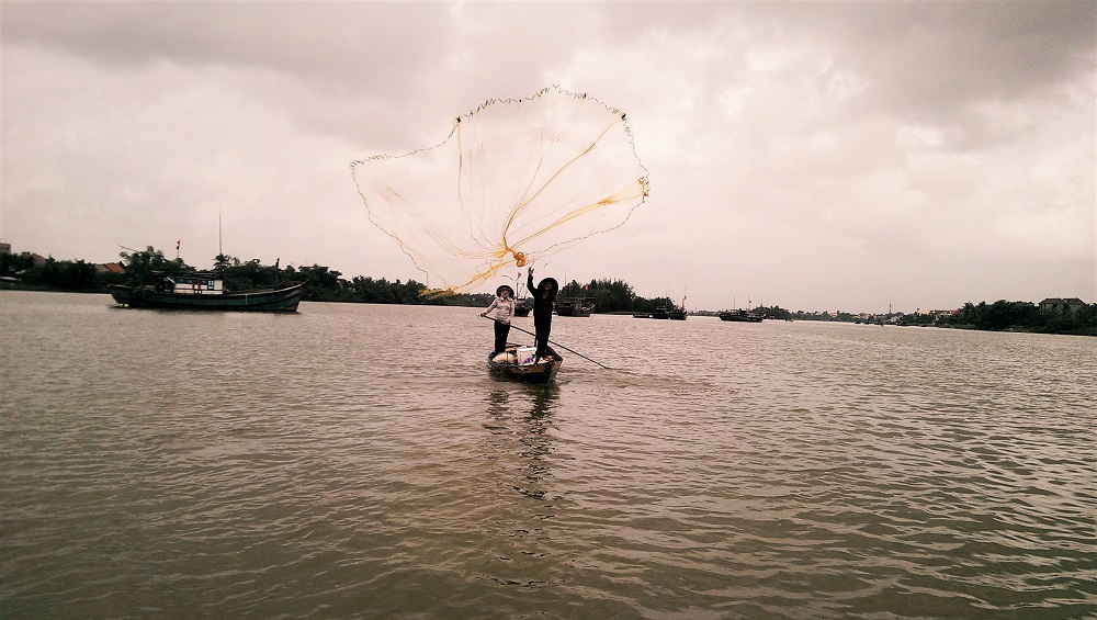 Traditional fishermen casting a net on the Thu Bon River in Hoi An
