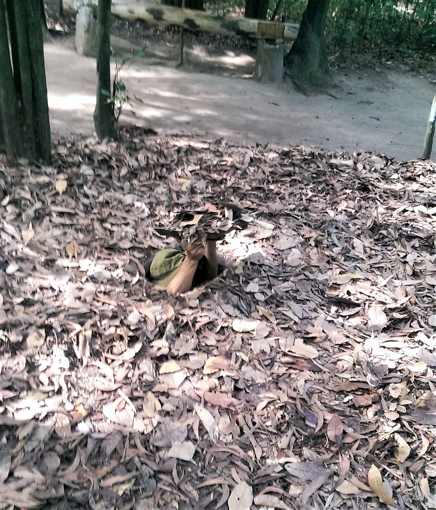A guide demonstrates a concealed entrance to the Cu Chi tunnels