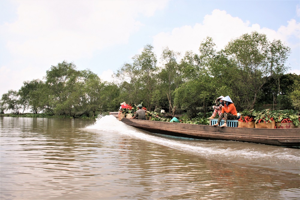 A small group of people transporting goods on a boat in Vinh Long in the Mekong Delta