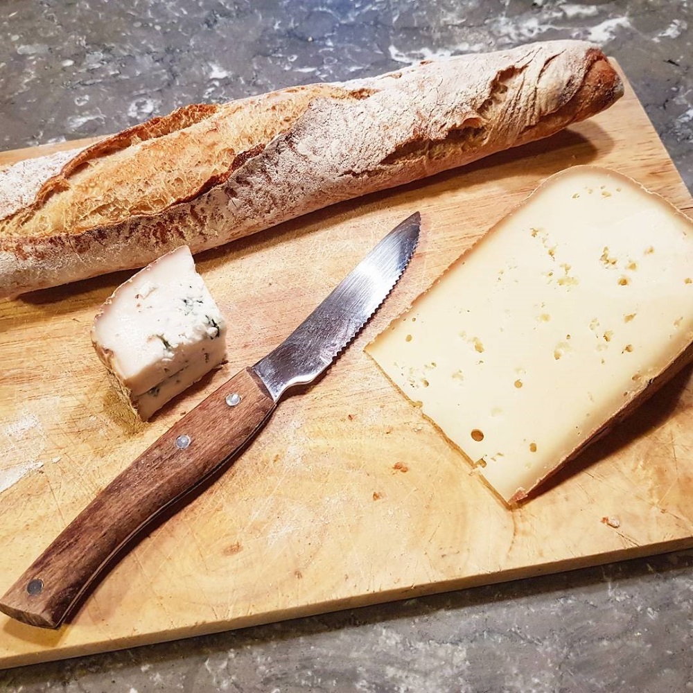 A wooden board with cheese and bread